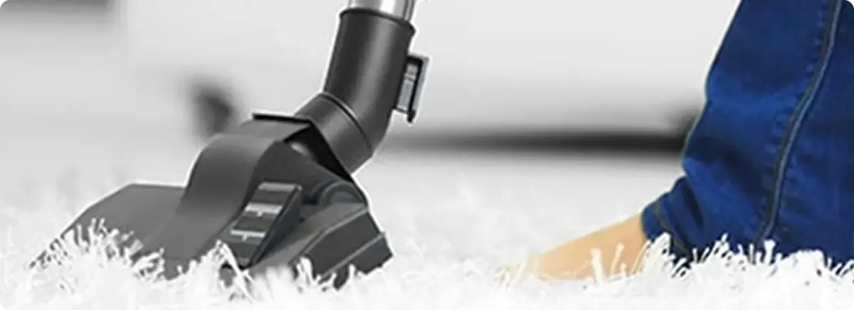 Close-up of a professional vacuuming a white carpet in Wetmore.